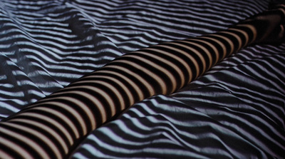 a close up of a bed with a black and white striped comforter