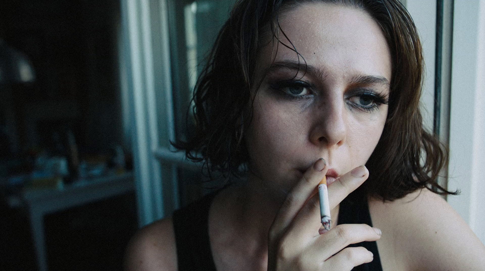 a woman smoking a cigarette in front of a window