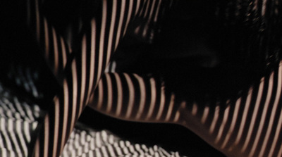 a close up of a person's legs with a stripped shirt on