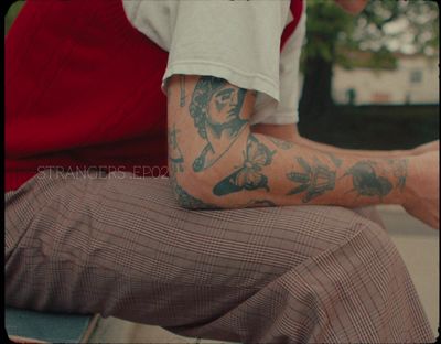 a man with tattoos sitting on a bench