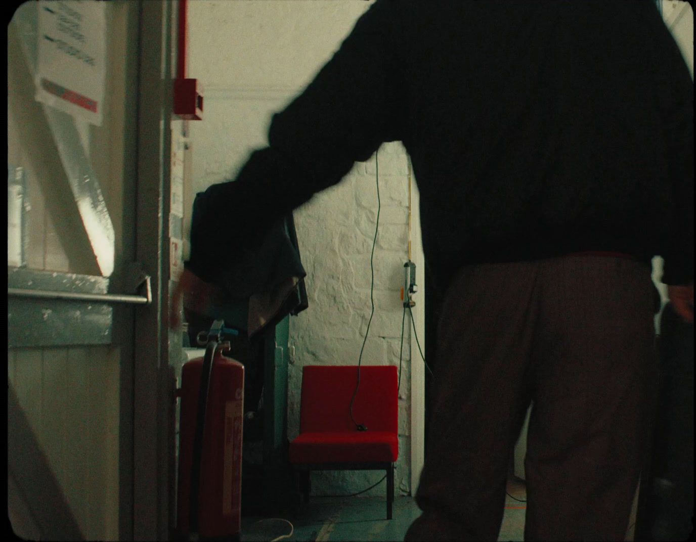 a man standing in a room next to a red chair