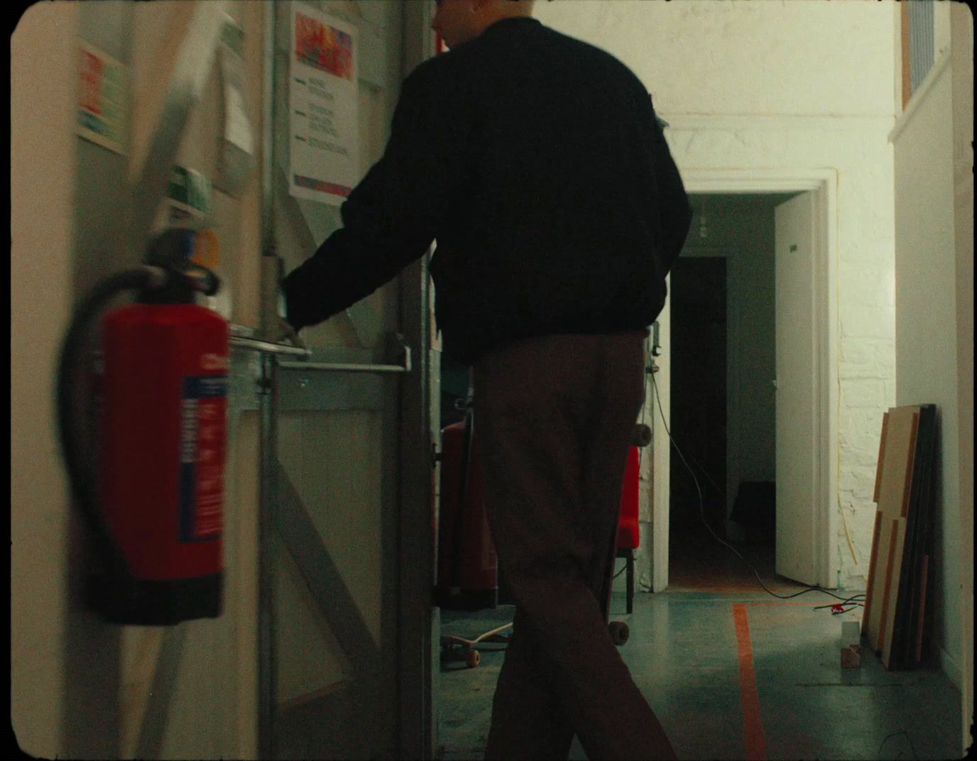 a man is entering a room with a red fire extinguisher