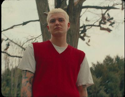 a man in a red vest standing in front of a tree