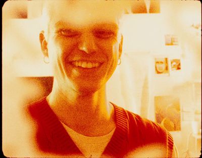 a man smiling in a kitchen with a refrigerator in the background