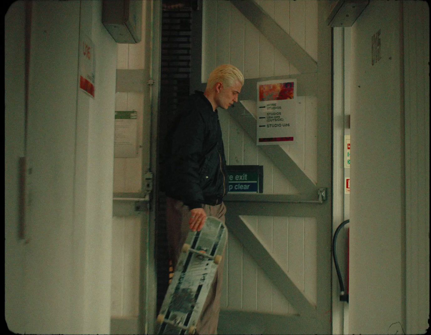 a man holding a skateboard standing in a doorway