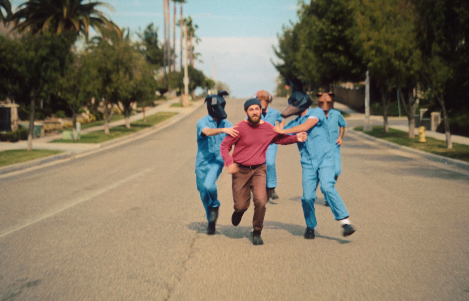 a group of men in blue jumpsuits running down a street