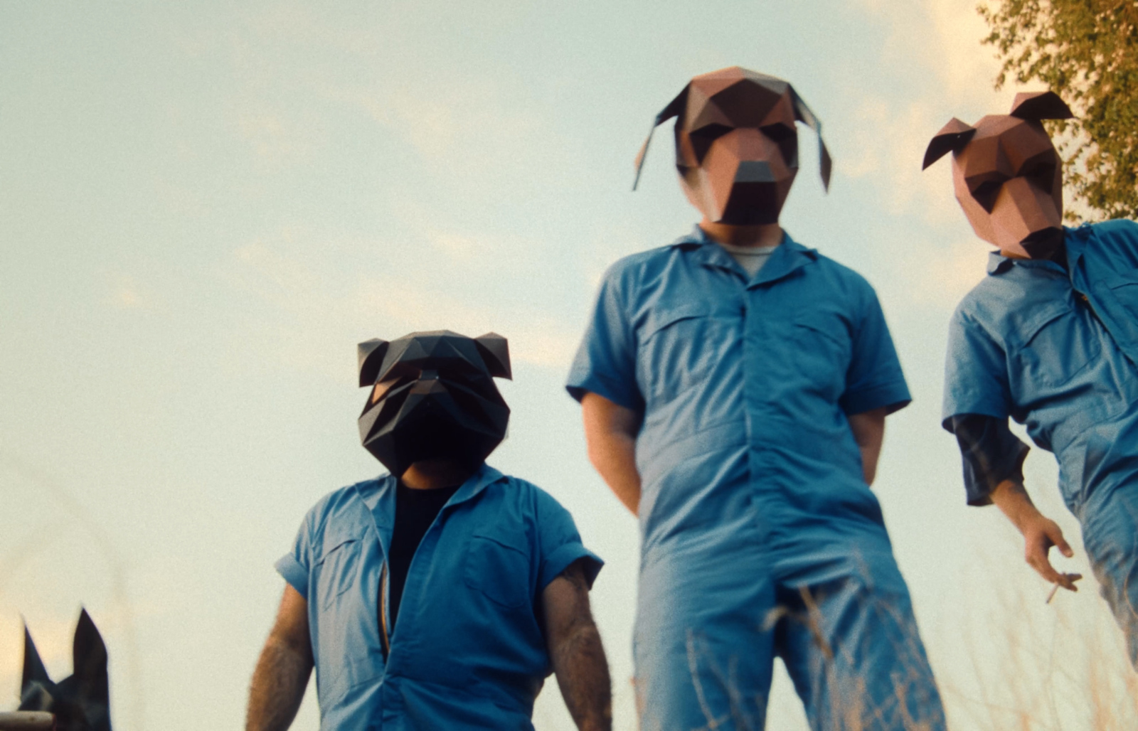 three people in blue jumpsuits are standing in a field