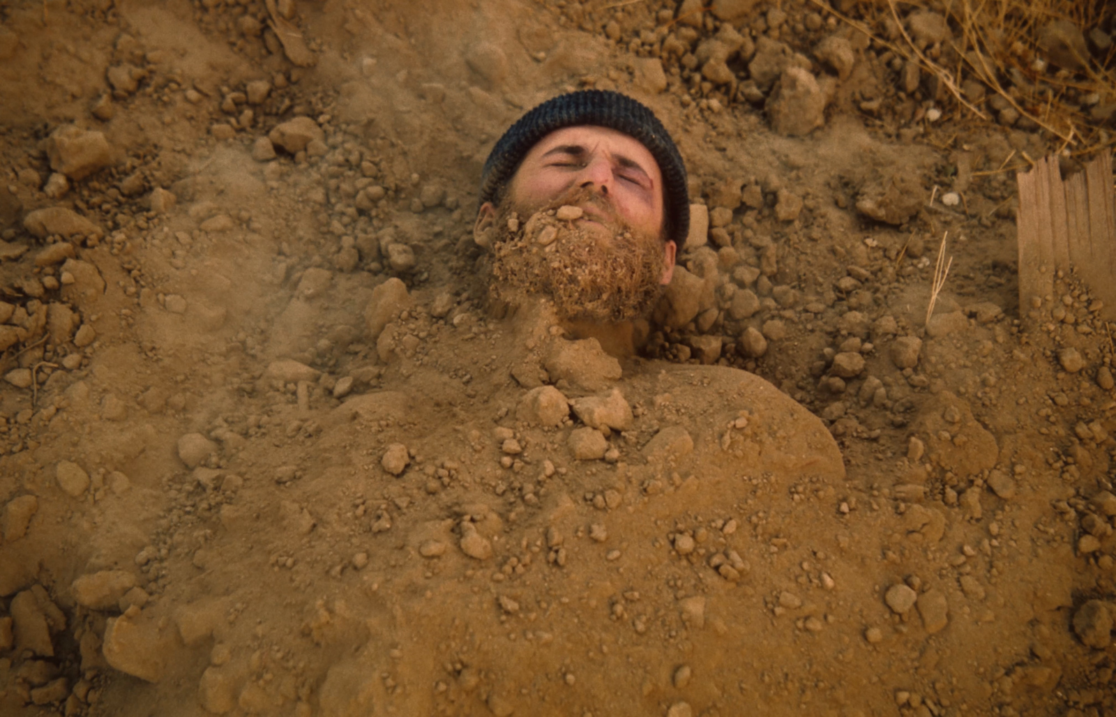 a man with a beard is buried in the dirt