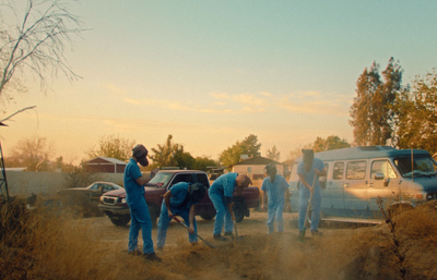 a group of people standing around a blue van