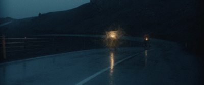 a couple of people walking down a road at night