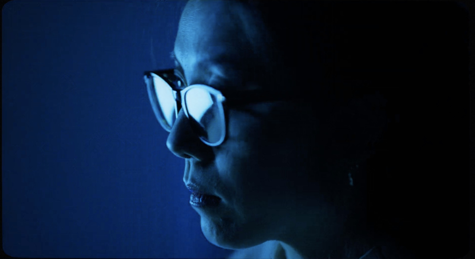 a woman wearing glasses in a dark room