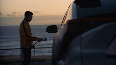 a man standing next to a car near the ocean