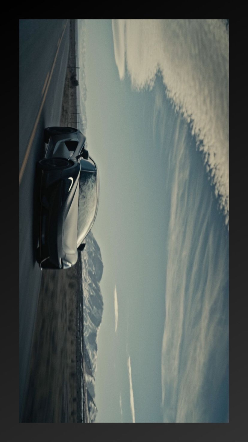 a car driving down a road next to snow covered mountains