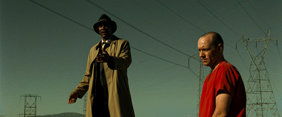 two men standing next to each other in front of power lines