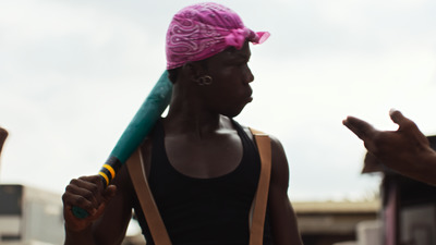 a woman with a pink bandana holding a green bat