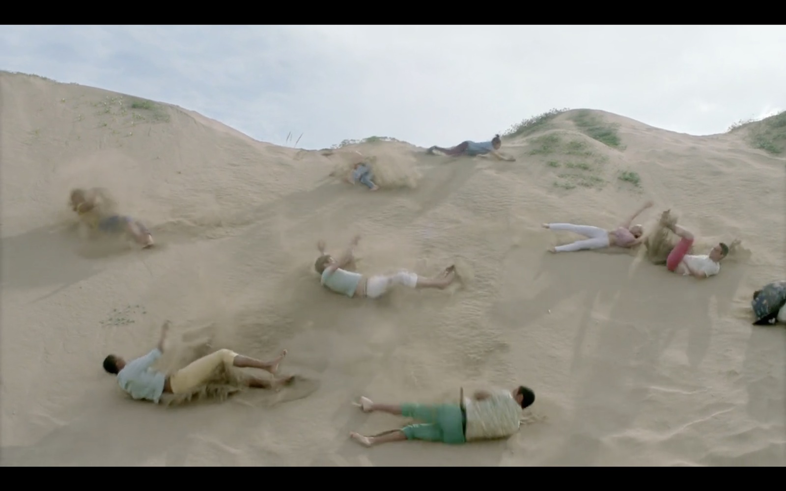 a group of people laying on top of a sandy hill