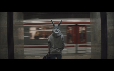 a person wearing a bunny mask standing in front of a train