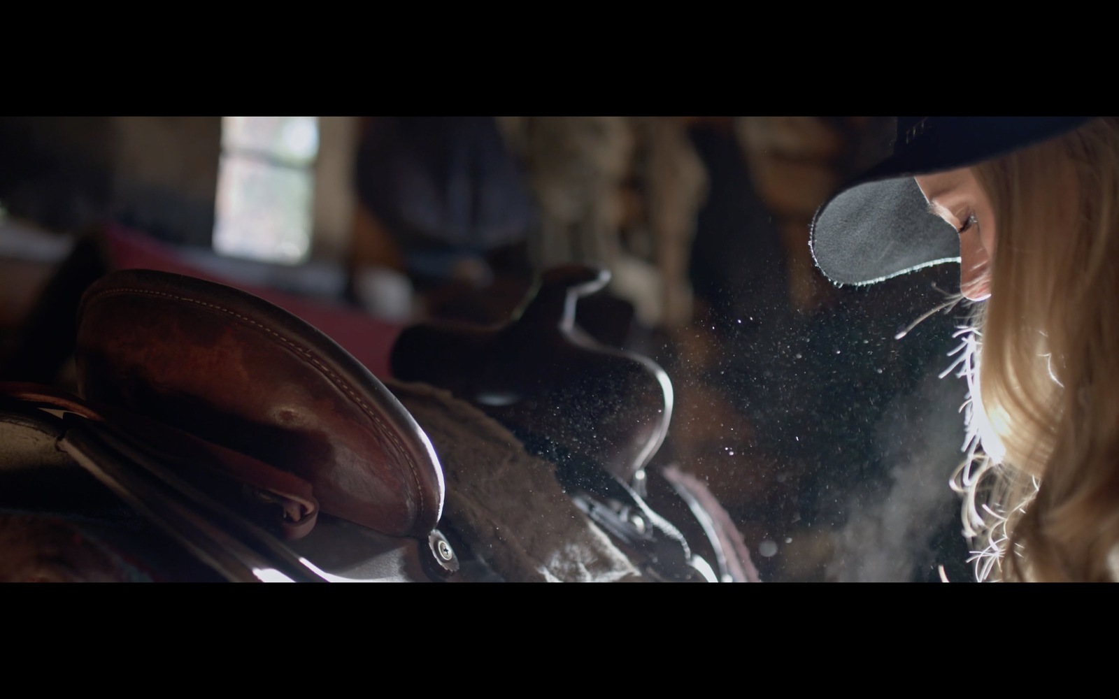 a woman looking at a horse's saddle through a window