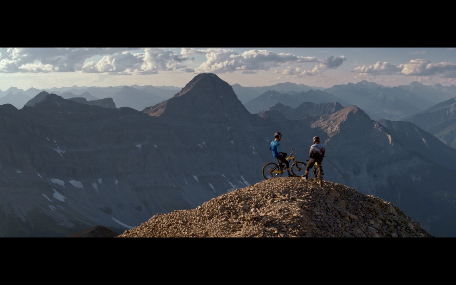 a couple of people riding bikes on top of a mountain