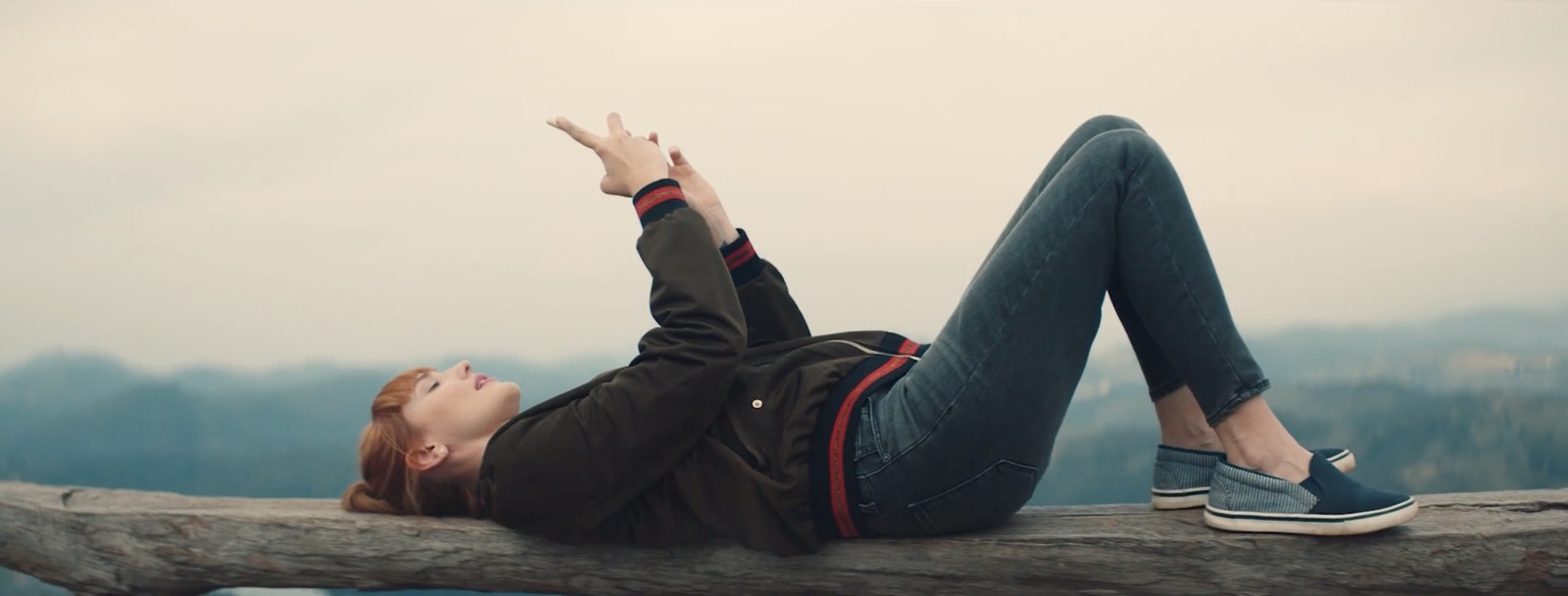 a woman laying on top of a tree branch