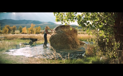 a woman standing next to a pile of hay