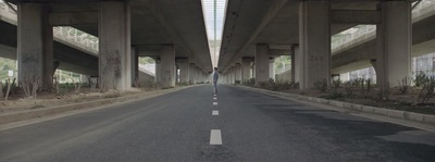 a person walking down a street under a bridge