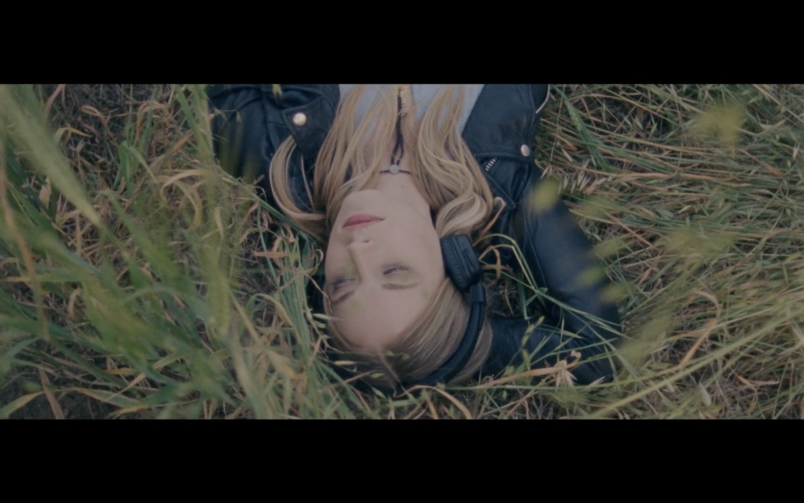 a woman laying in the grass with her eyes closed