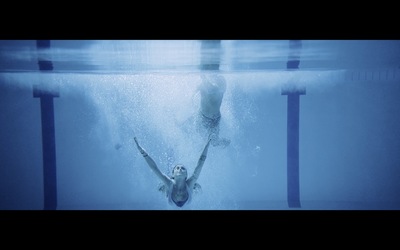 a man swimming in a pool with his hands in the air