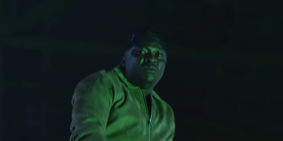 a man in a green jacket standing in front of a green light