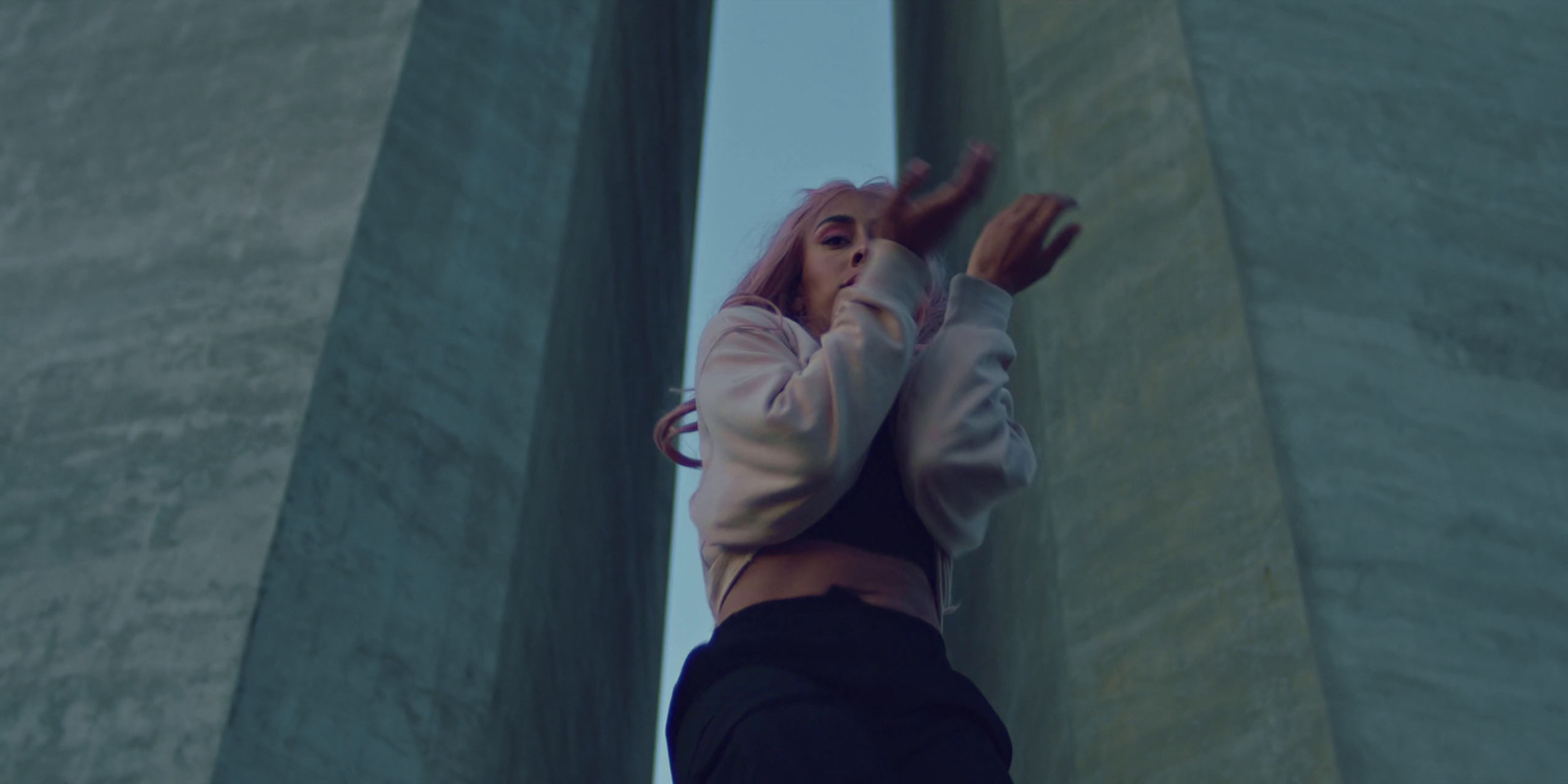 a woman with pink hair standing in front of a tall building