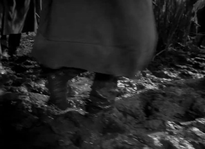 a black and white photo of a person walking in mud