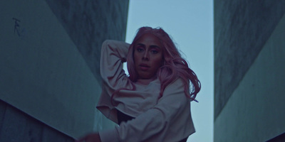 a woman with pink hair is leaning against a wall