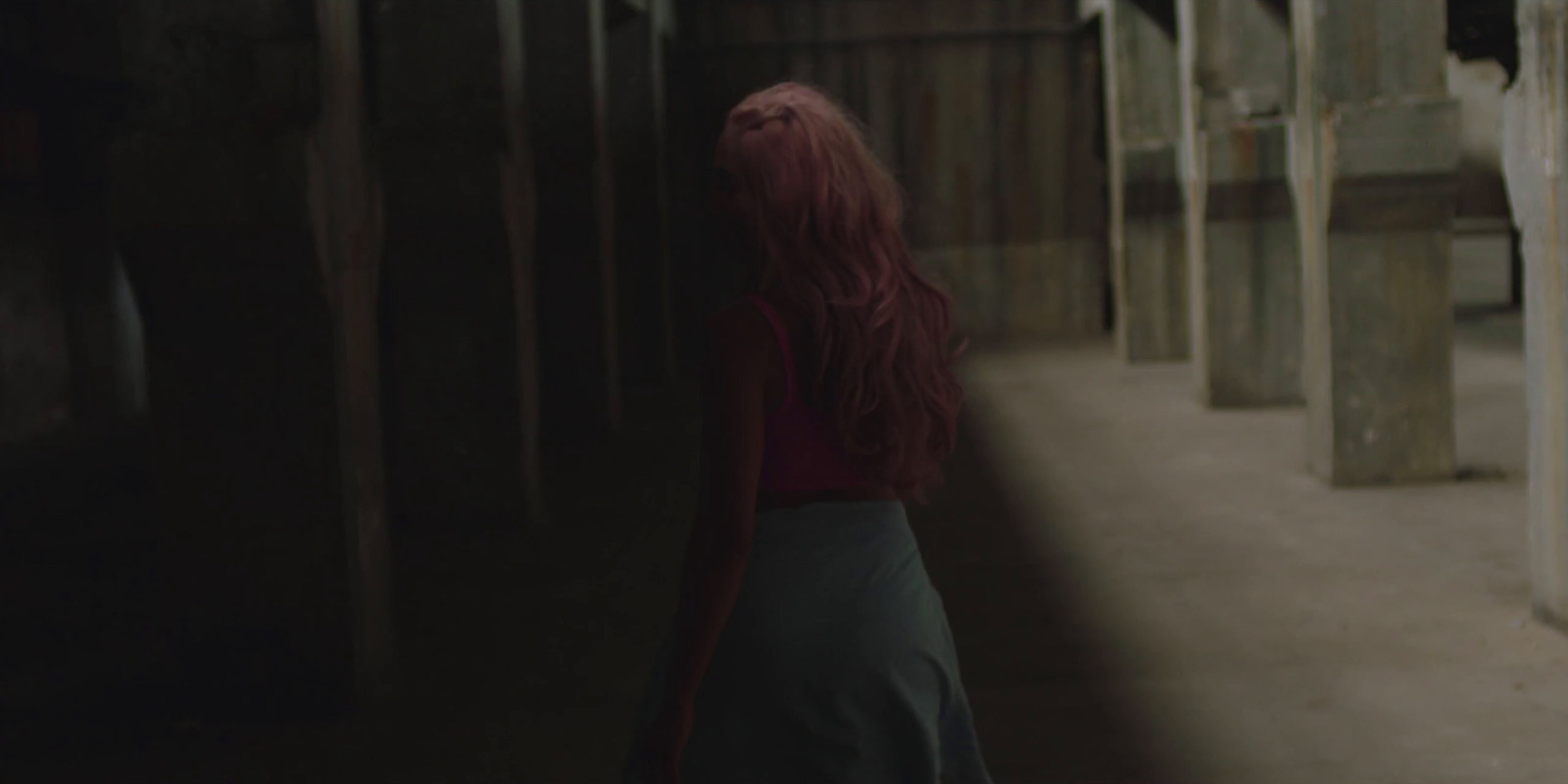 a girl is walking down a hallway in a dark room