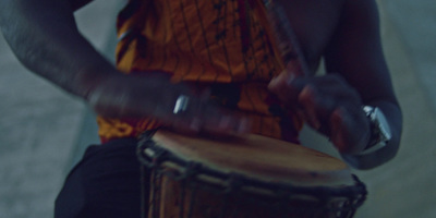 a man is playing a djembe in front of a building