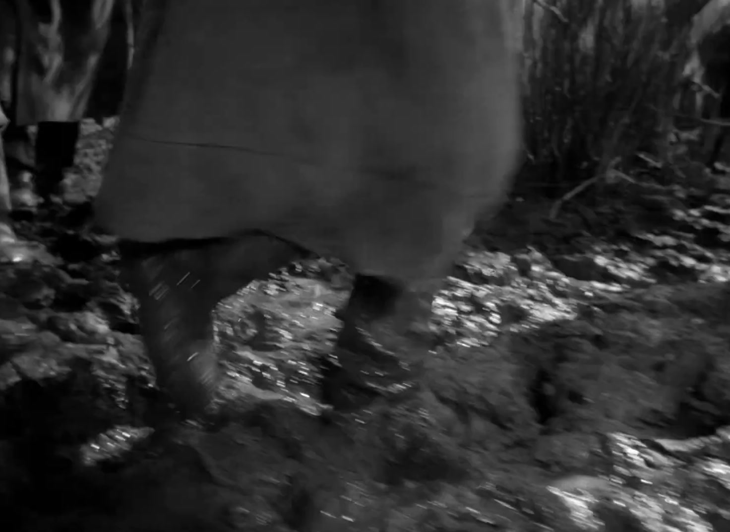 a black and white photo of a person walking in the mud