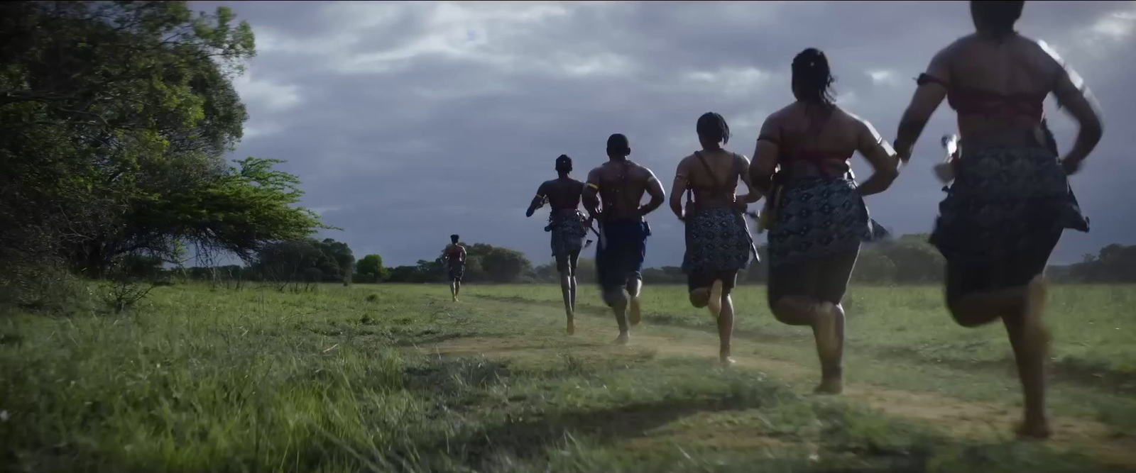 a group of people running down a dirt road