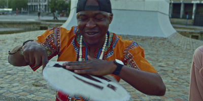 a man in an african outfit is holding a drum