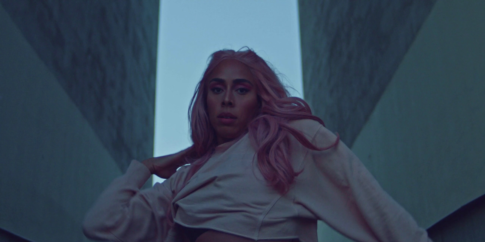 a woman with pink hair is posing in front of a building