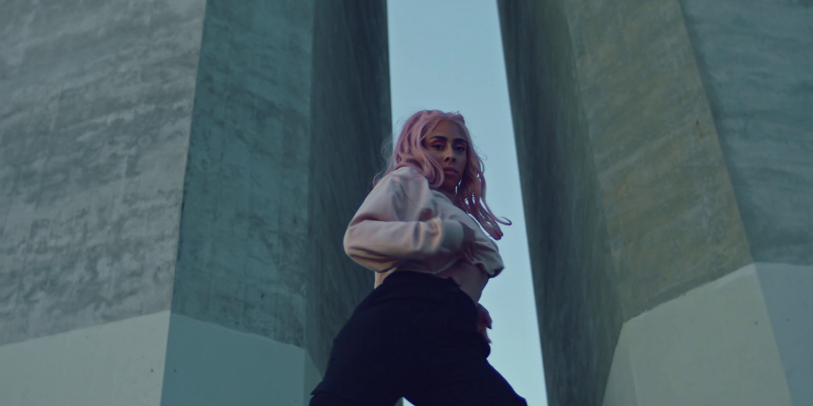 a girl with pink hair standing in front of pillars