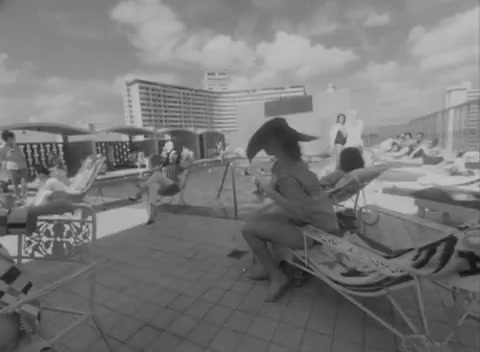 a black and white photo of a woman sitting on a beach chair