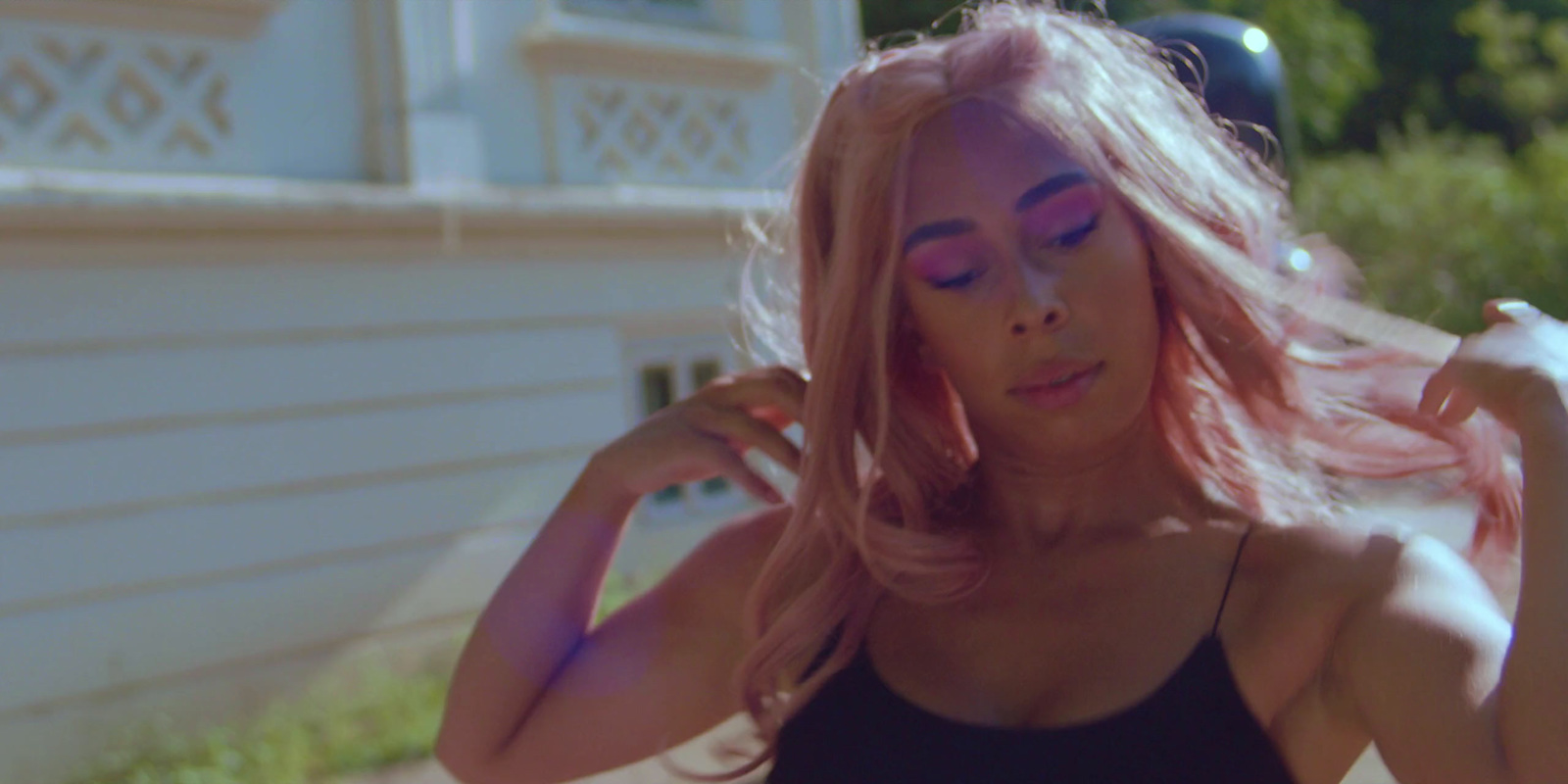 a woman with pink hair posing in front of a house