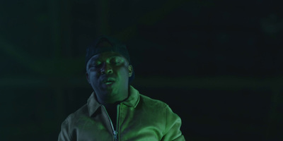 a man in a green jacket standing in front of a green light