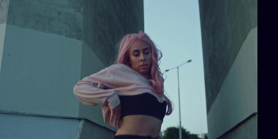 a woman with pink hair is standing in front of a wall