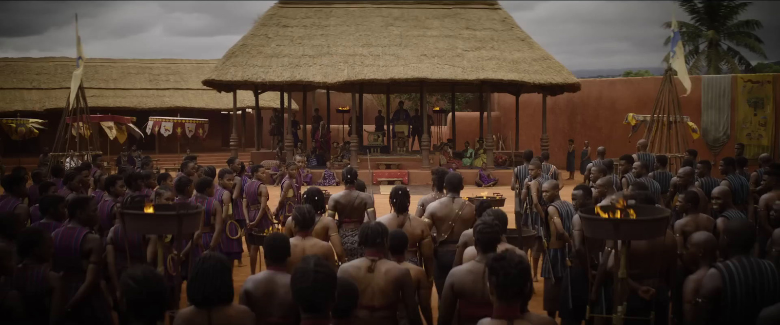 a large group of people standing around in front of a hut