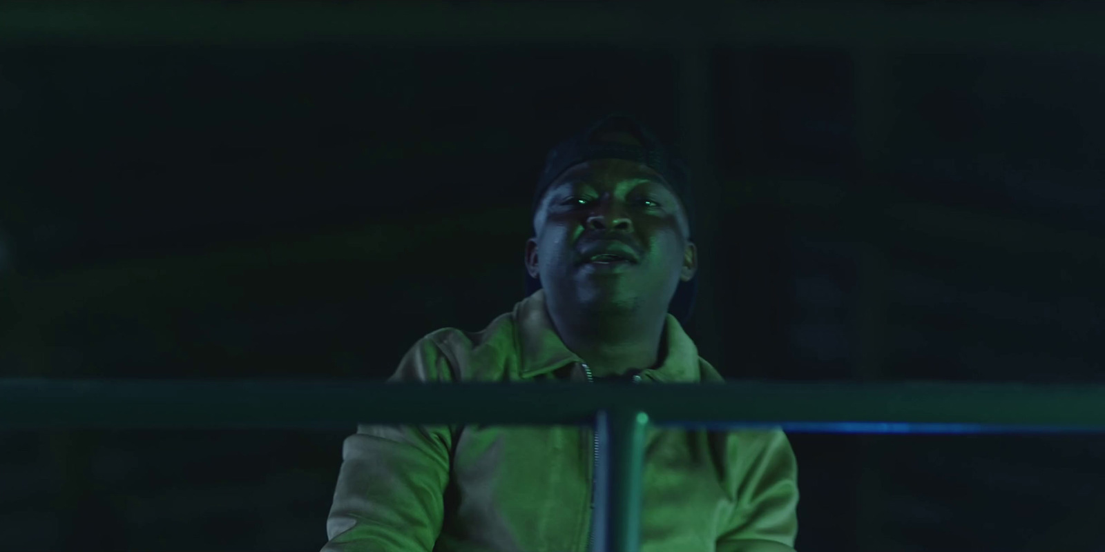 a man in a green jacket standing on a railing