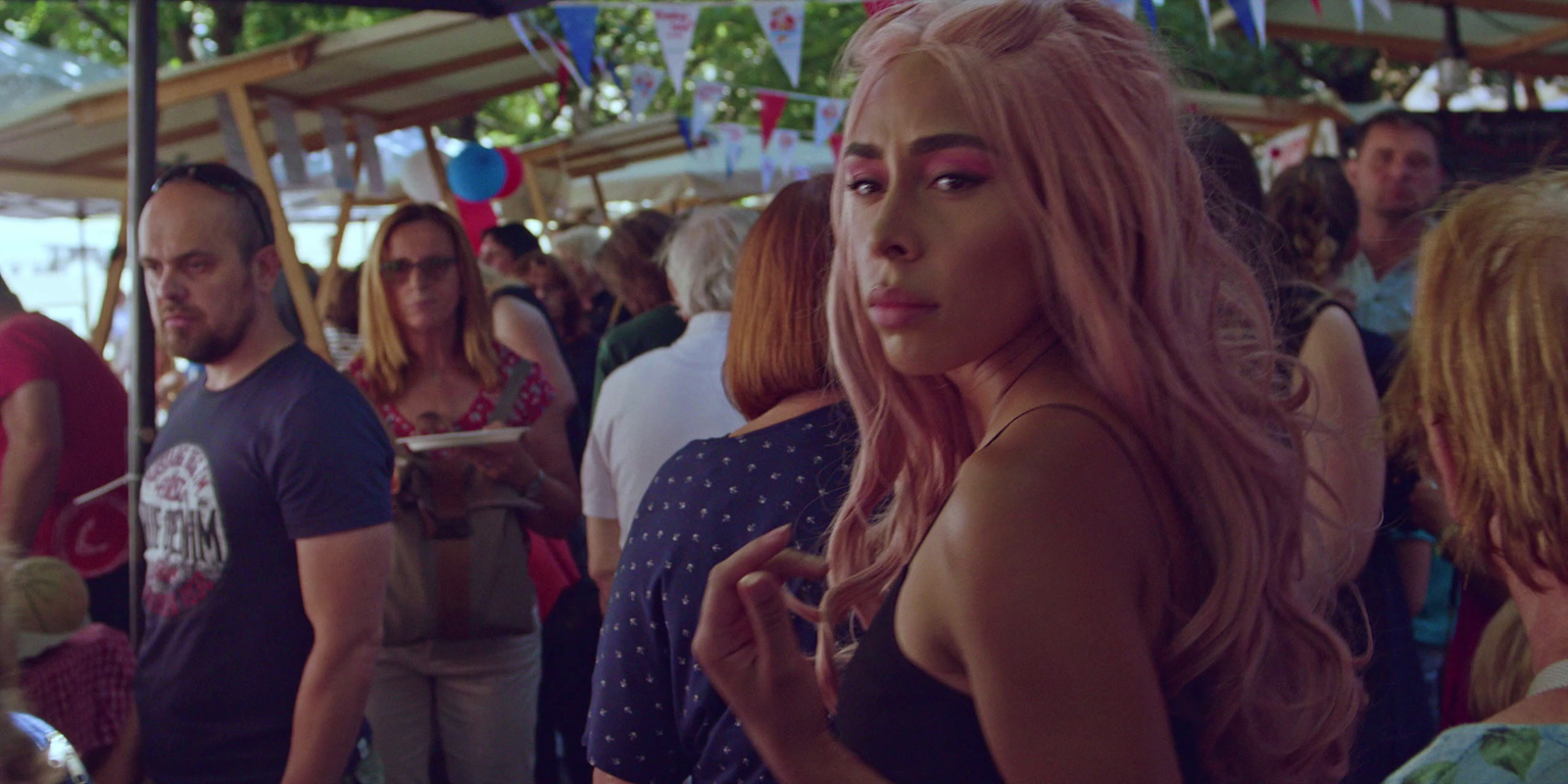 a woman with pink hair standing in a crowd