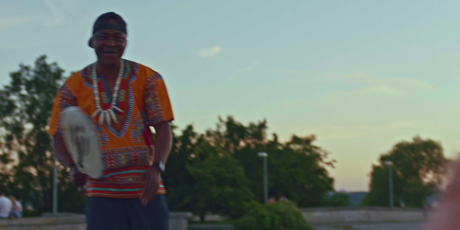 a man in a colorful shirt is holding a drum