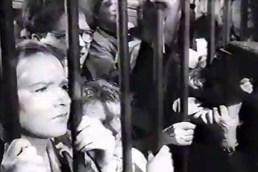 a black and white photo of a group of people behind bars