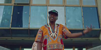 a man in an african outfit is standing in front of a building