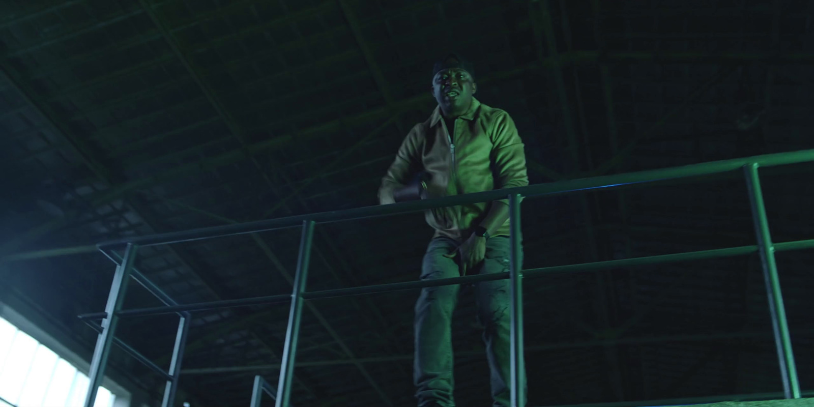 a man standing on a metal railing in a warehouse